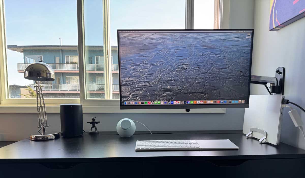 home office desk with apple MacBook laptop in dock connected to mounted Samsung monitor with keyboard and mouse and a Sonos speaker