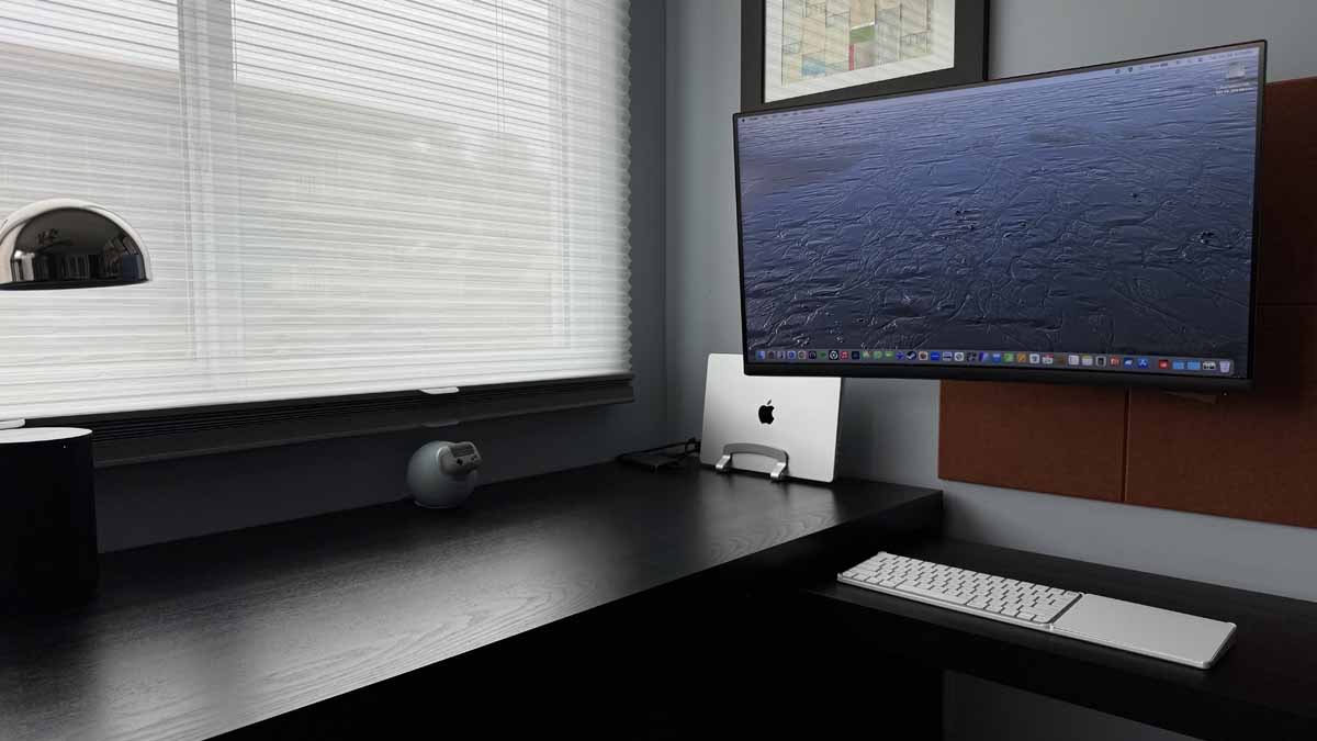 macbook computer with external monitor mounted over a tidy desk 3